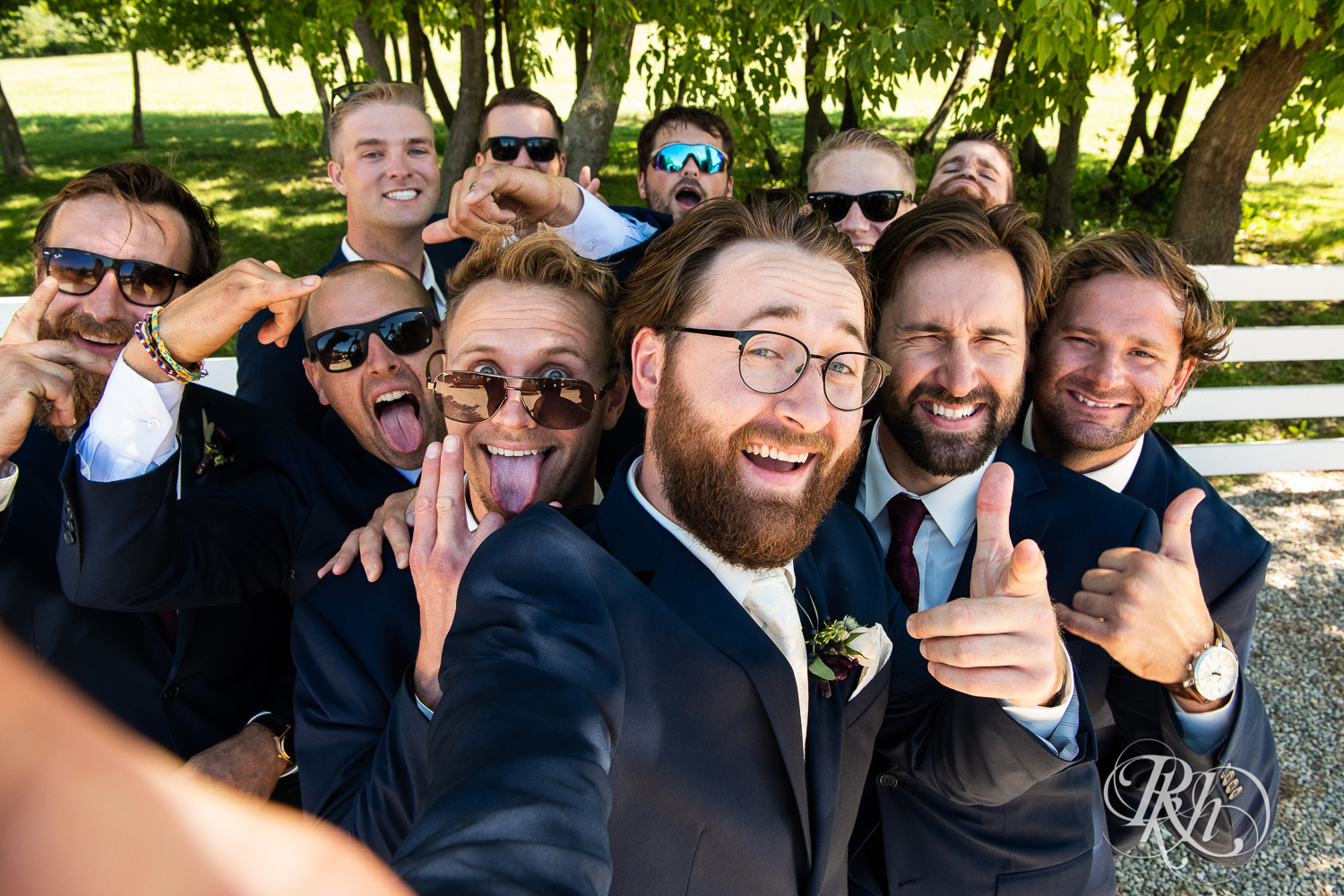 Wedding party in blue suits laugh and smile at Green Acres Event Center in Eden Prairie, Minnesota.