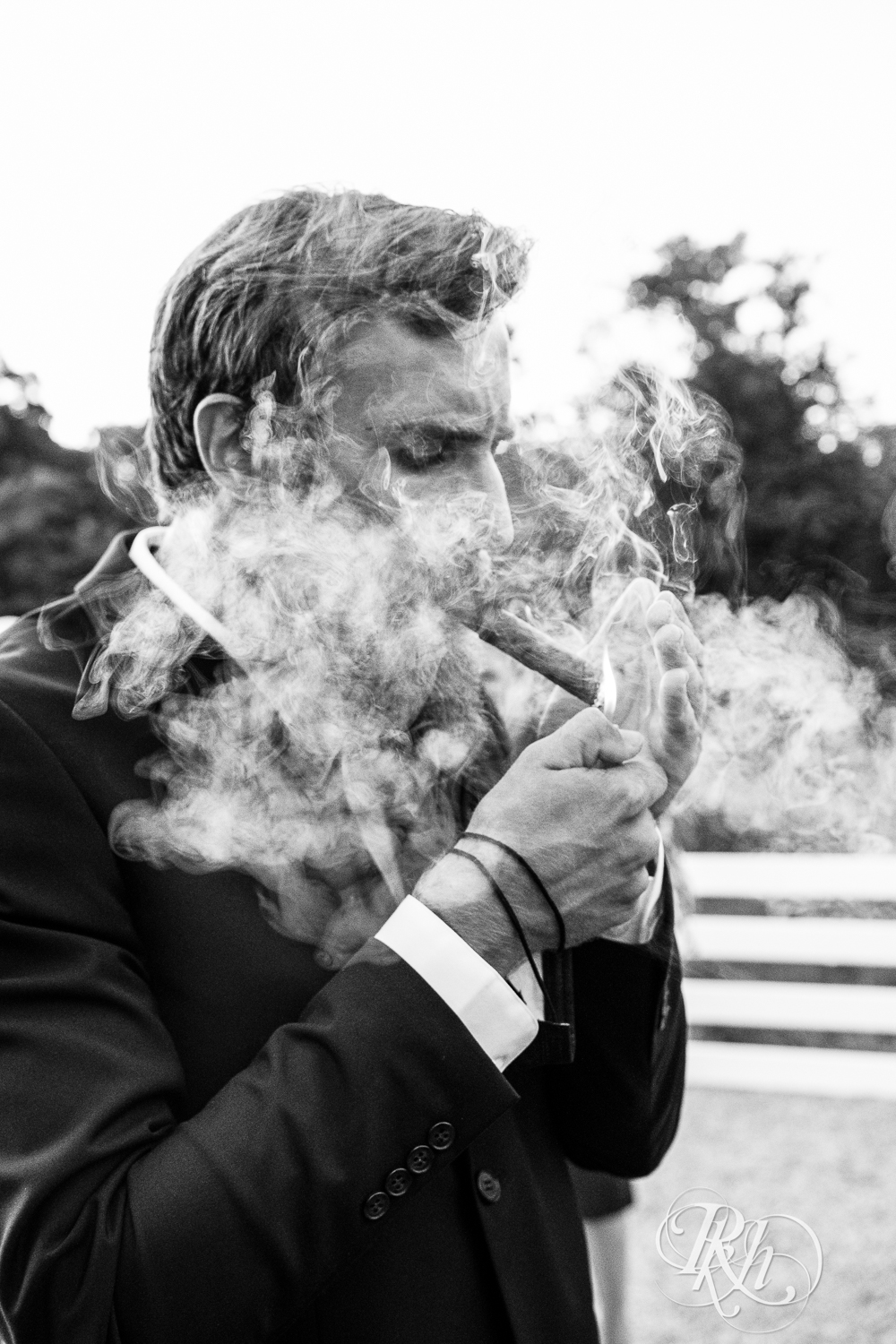 Groomsman smokes cigar at Green Acres Event Center in Eden Prairie, Minnesota.