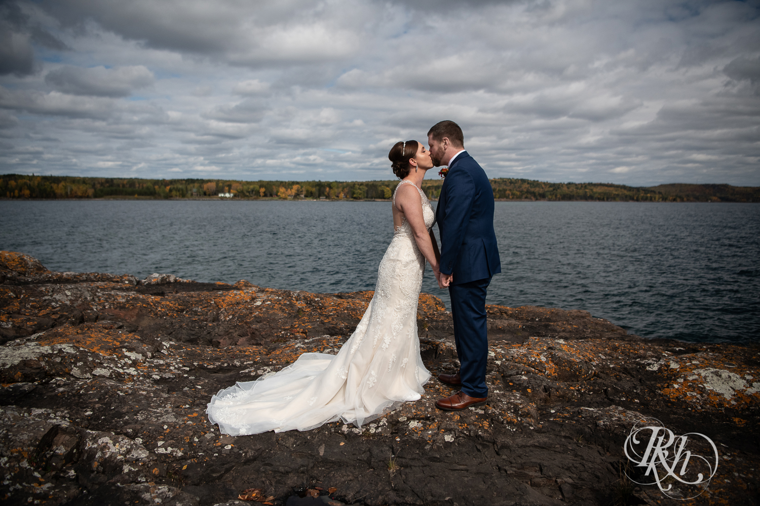Bride and groom kiss on rock in front of Lake Superior at Superior Shores Resort in Two Harbors, Minnesota.