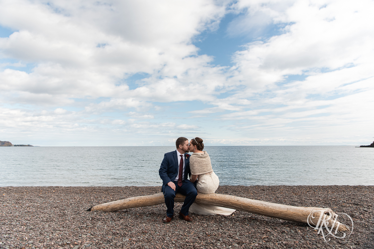 Bride and groom kiss on beach of Lake Superior at Superior Shores Resort in Two Harbors, Minnesota.