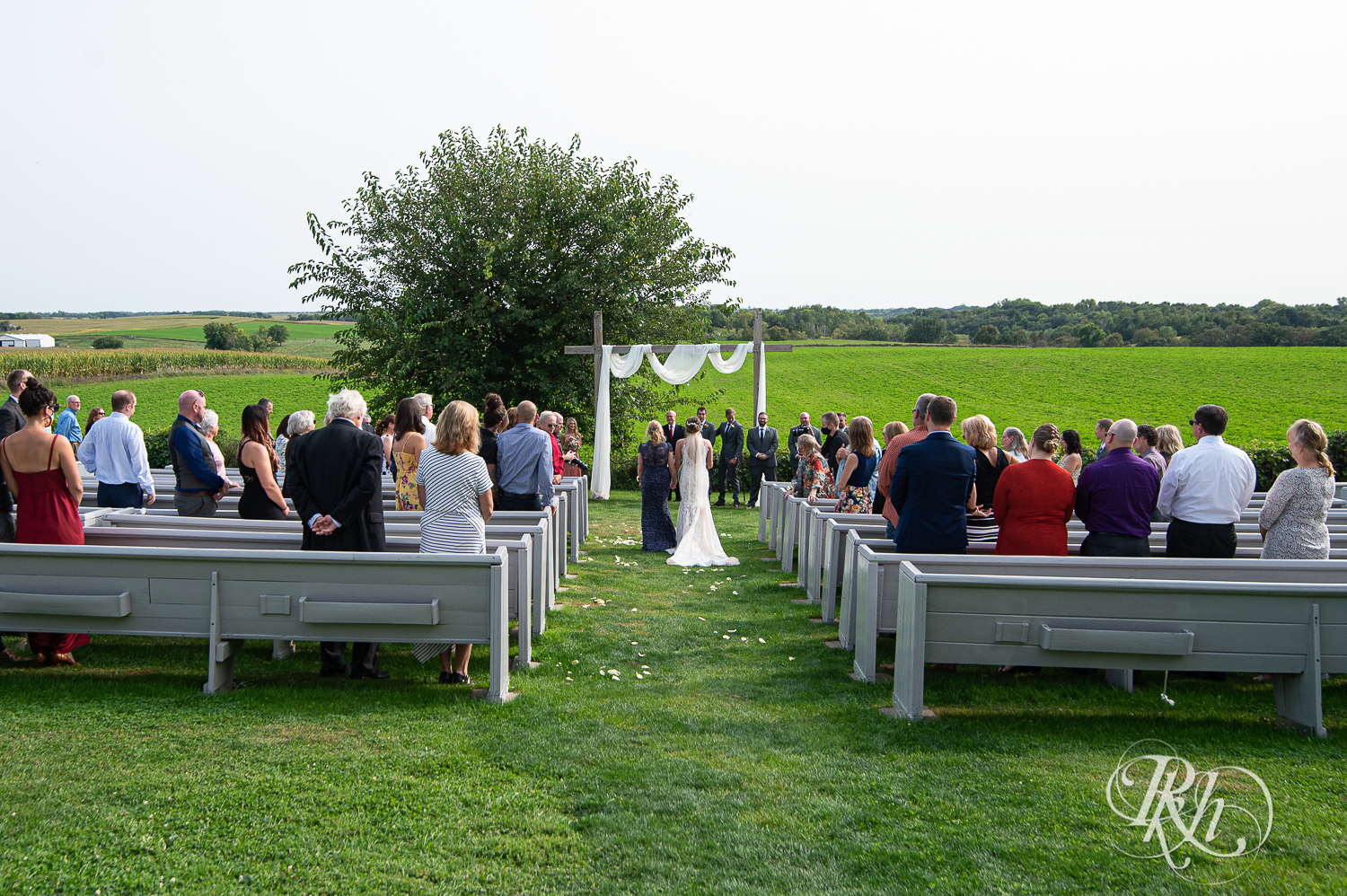 Bride walks down the aisle with mom during wedding ceremony at Legacy Hills Farm in Welch, Minnesota.
