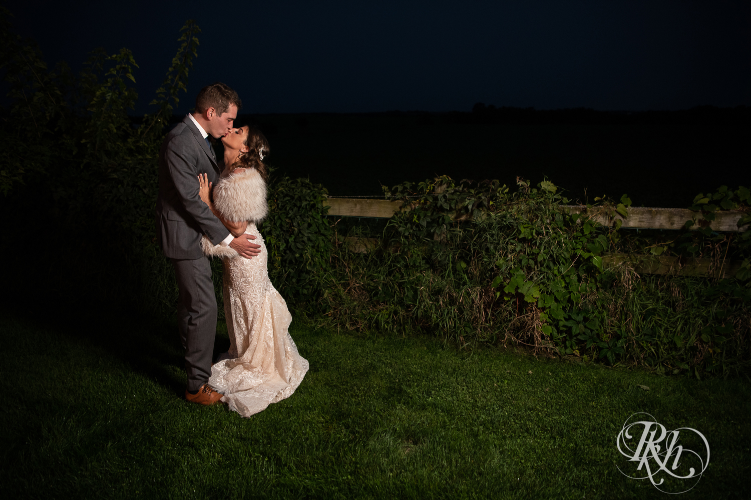 Bride smiles in fur stole and dress at night at Legacy Hills Farm in Welch, Minnesota.