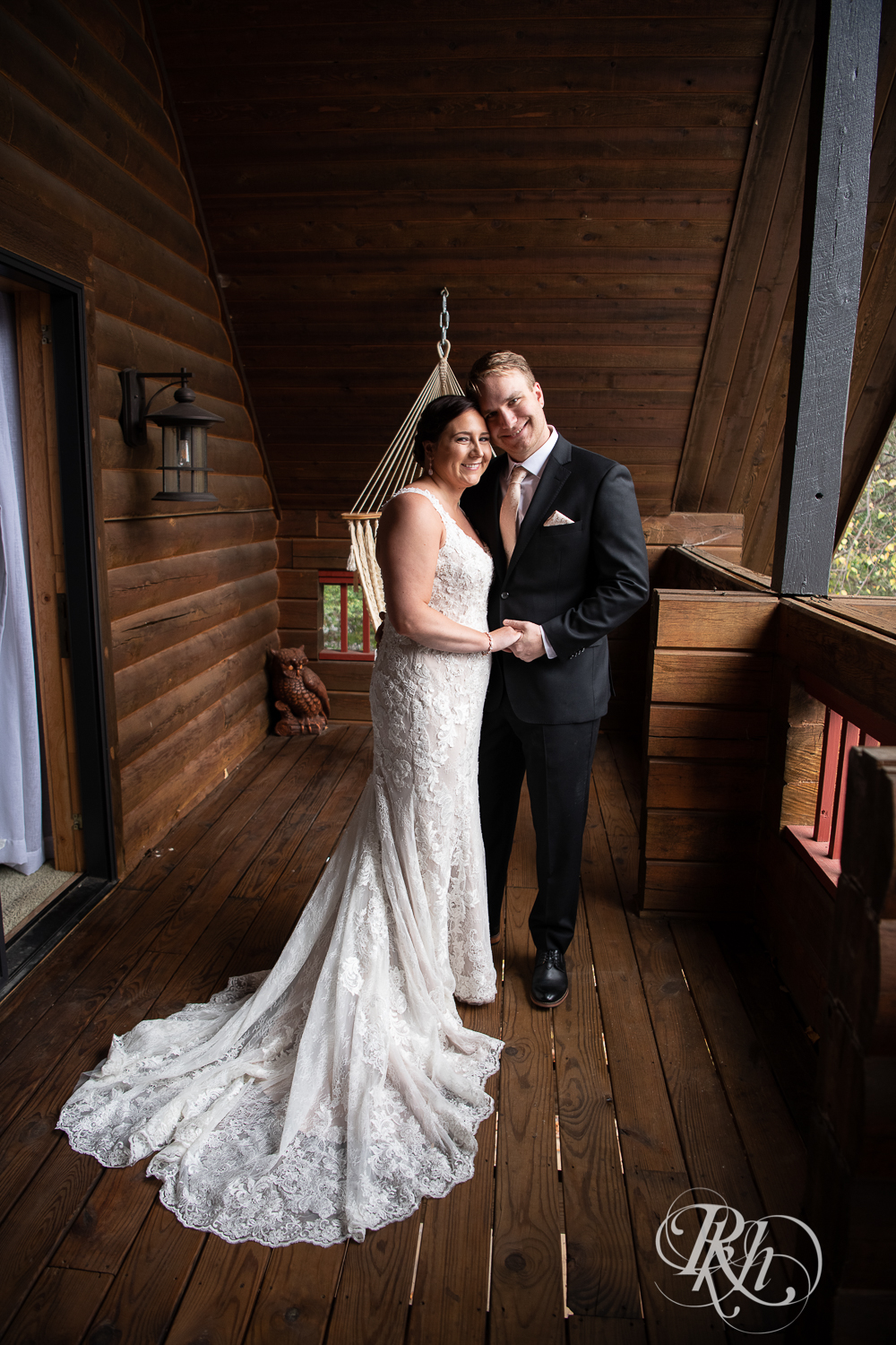 Bride and groom smile on balcony at a cabin A-frame in Stillwater, Minnesota.