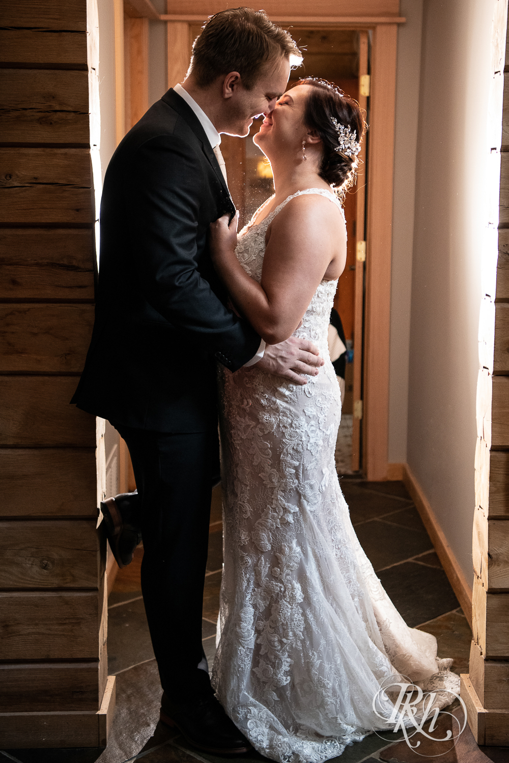 Bride and groom smile in the hallway at a cabin A-frame in Stillwater, Minnesota.