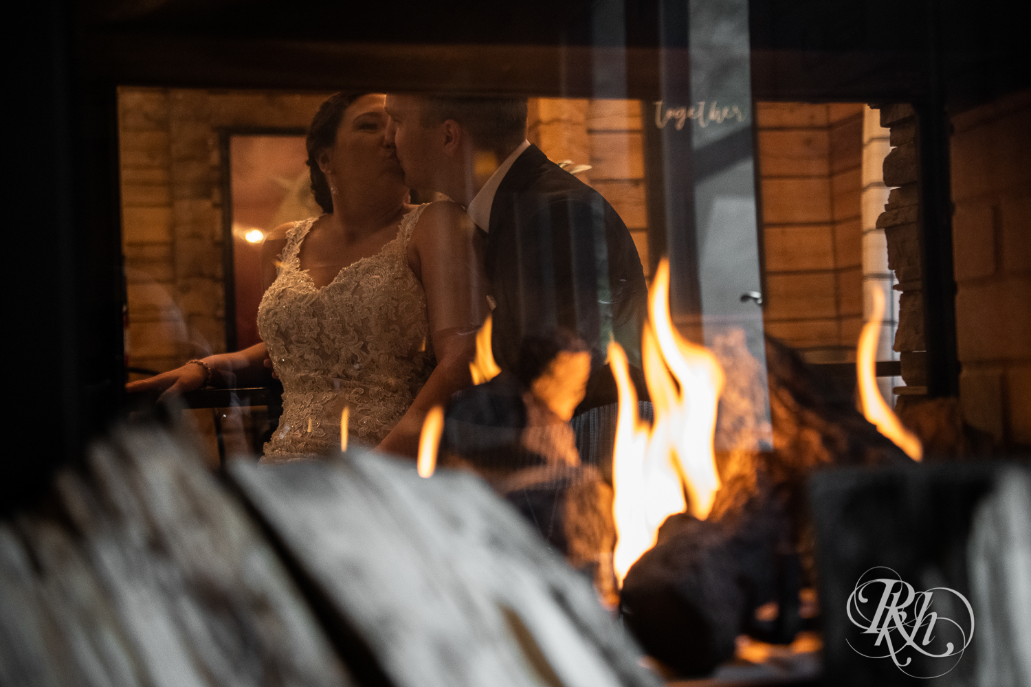 Bride and groom kiss by the fireplace at a cabin A-frame in Stillwater, Minnesota.