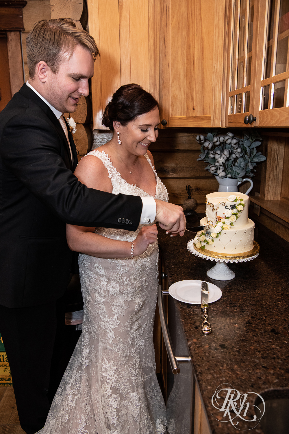 Bride and groom cut cake at wedding in cabin in Stillwater, Minnesota.