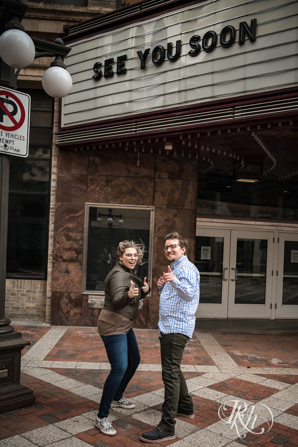 Blond woman with glasses and man with glasses pointing in front of the Palace Theater in Saint Paul, Minnesota.