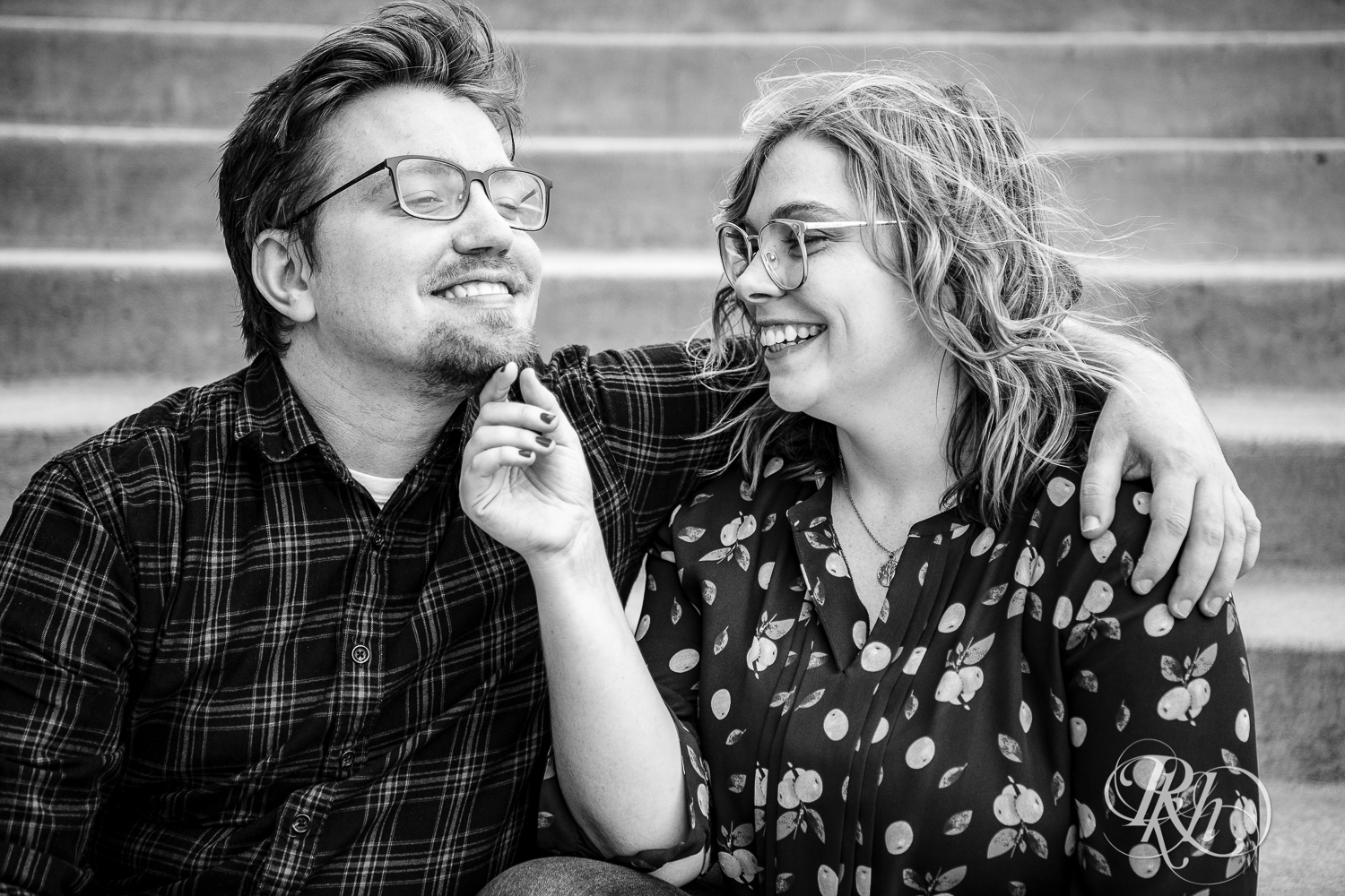 Blond woman with glasses and man with glasses smile on steps in Saint Paul, Minnesota.