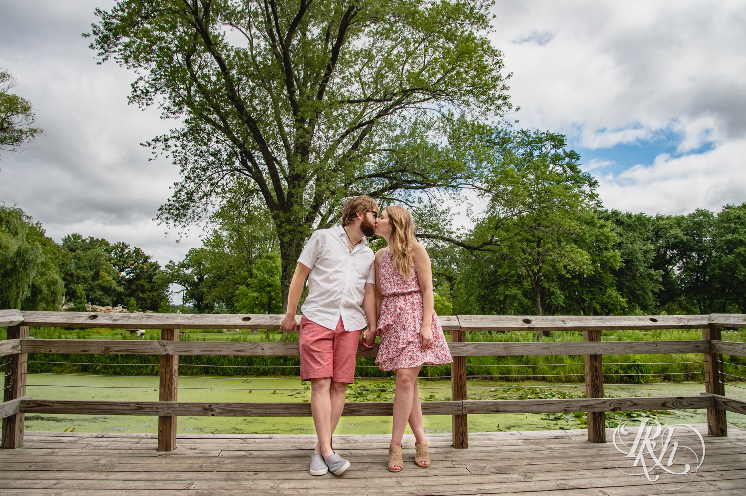 Man and woman in dress kiss on dock in Lake Phalen in Saint Paul, Minnesota.