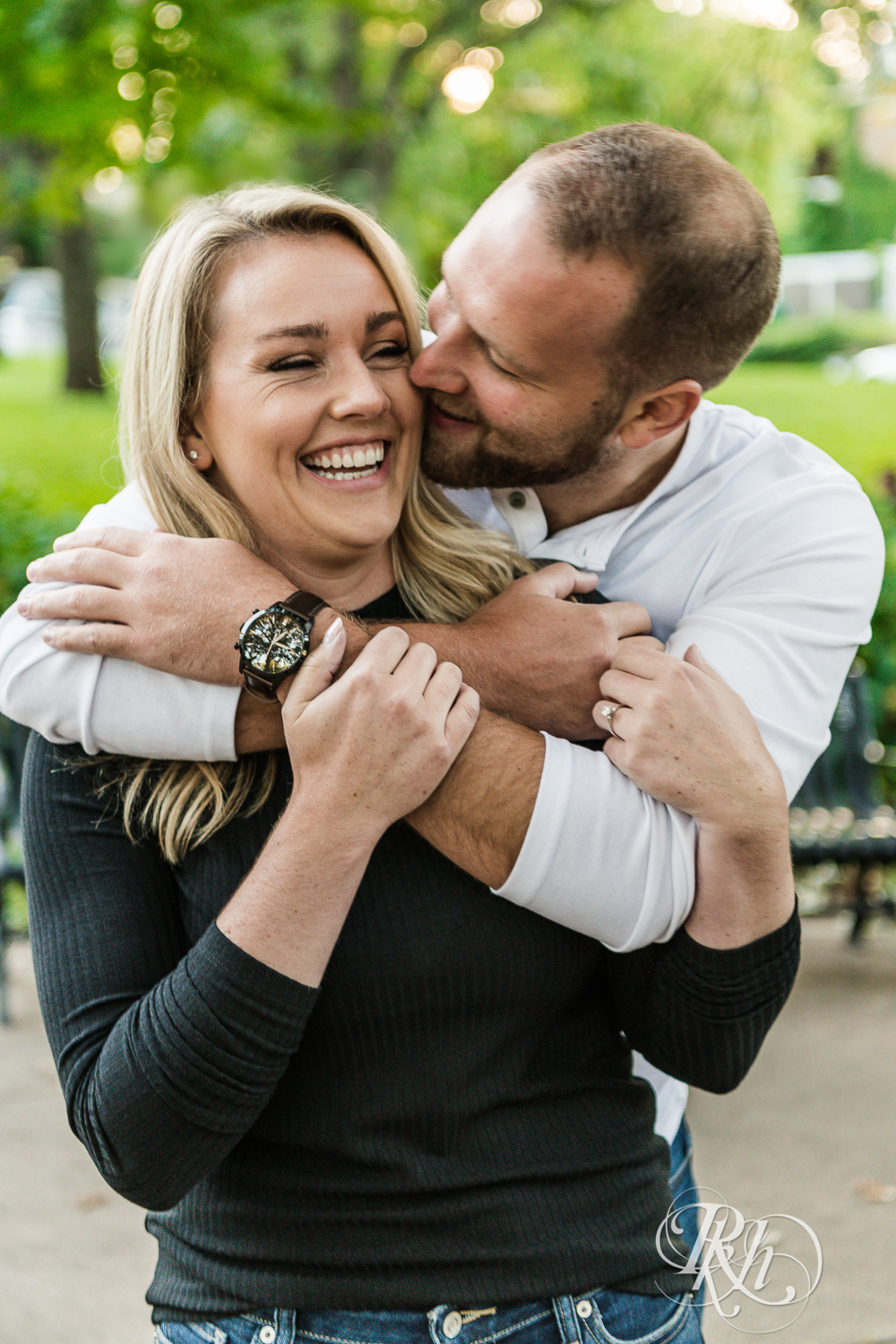 Blonde man and woman in sweaters and jeans hug at sunset in Irvine Park in Saint Paul, Minnesota.