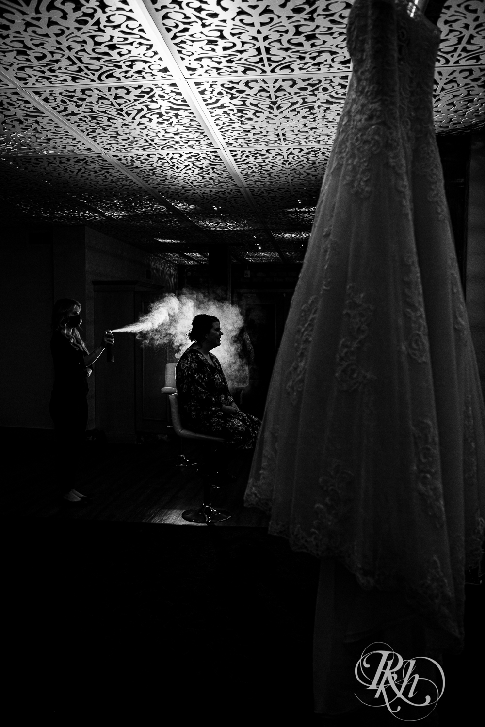 Bride getting hairsprayed with wedding dress in forefront at Minneapolis Event Center in Minneapolis, Minnesota.
