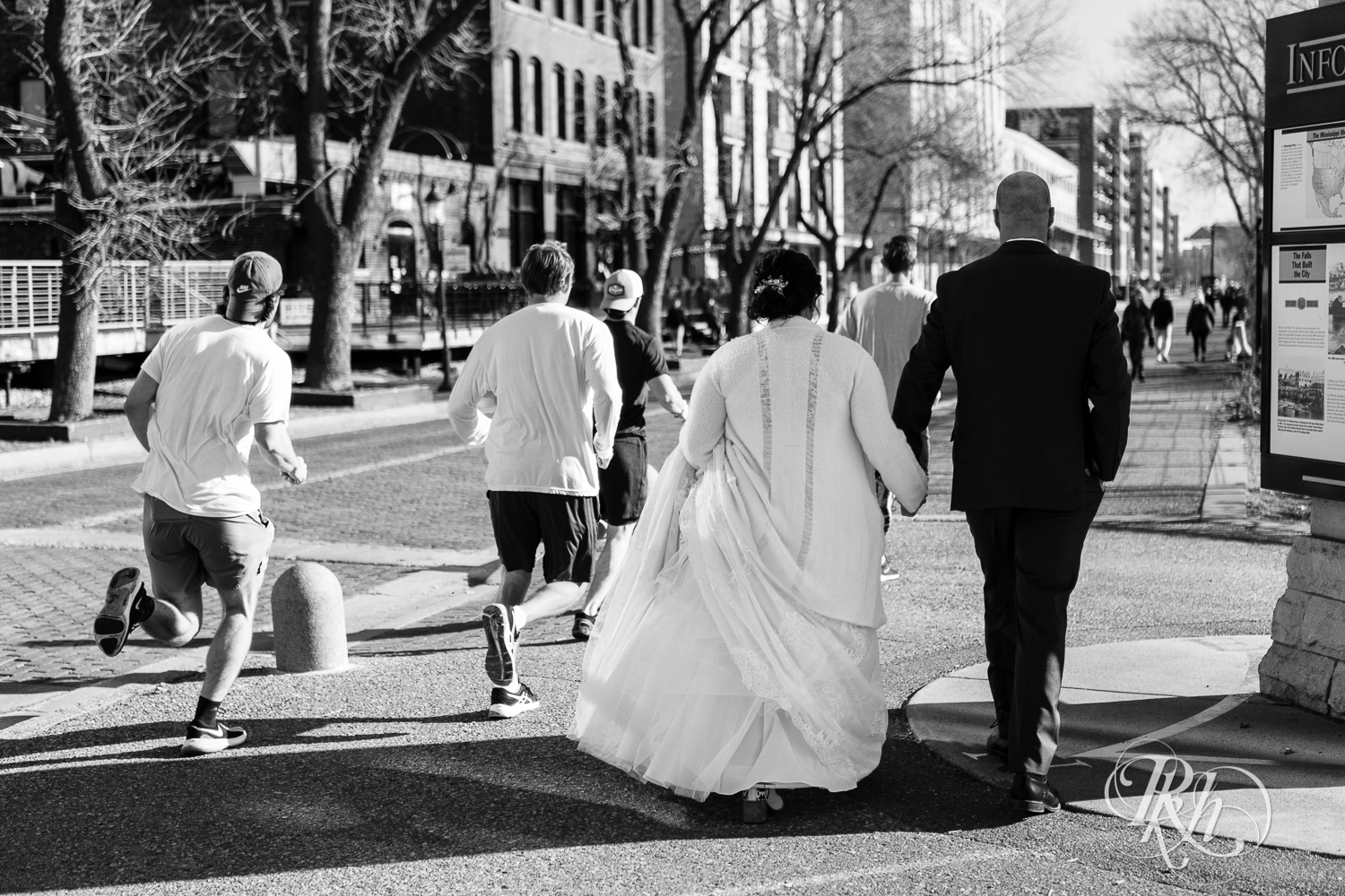 Bride and groom walk down the street in Saint Anthony Main in Minneapolis, Minnesota.