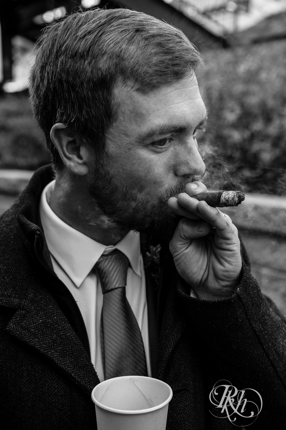 man holding coffee cup and smoking cigar