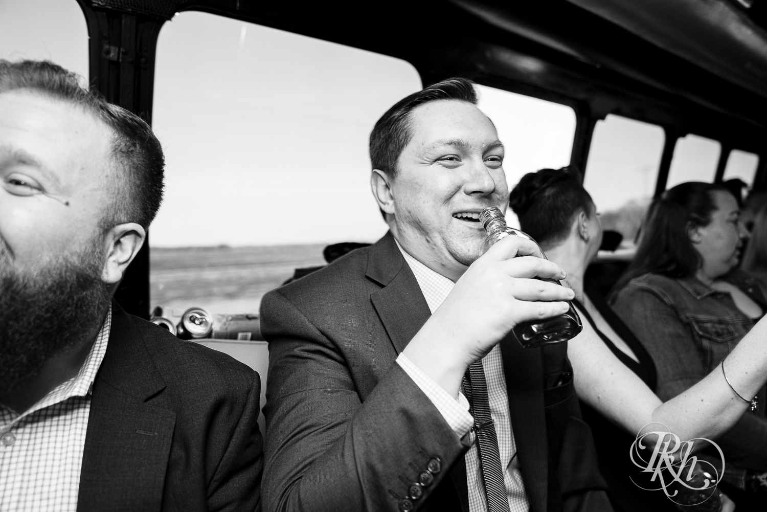 Bride and groom drink with wedding party on party bus after wedding ceremony in Faribault, Minnesota.