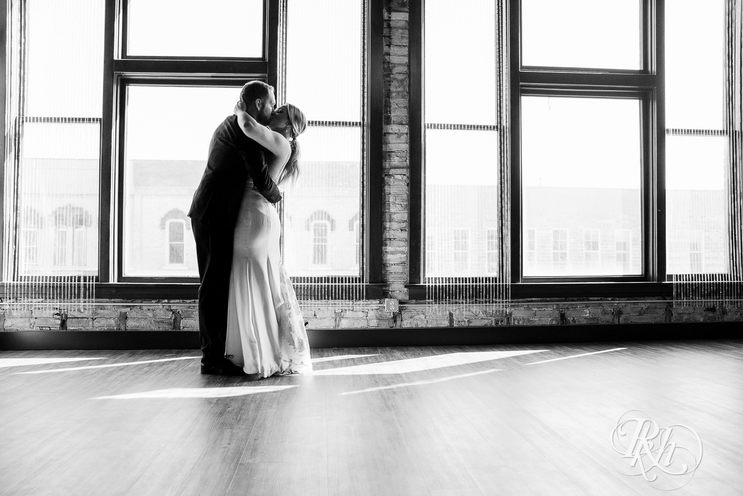 Bride and groom in black suit dance in front of a window in the 3 Ten Event Center in Faribault, Minnesota.