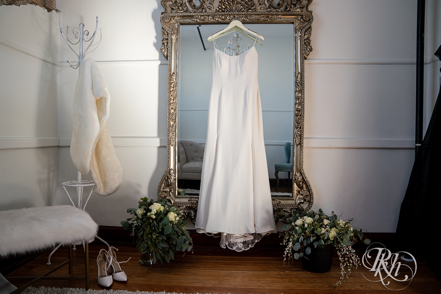 Wedding dress hangs on mirror with flowers surrounding it at the 3 Ten Event Center in Faribault, Minnesota.