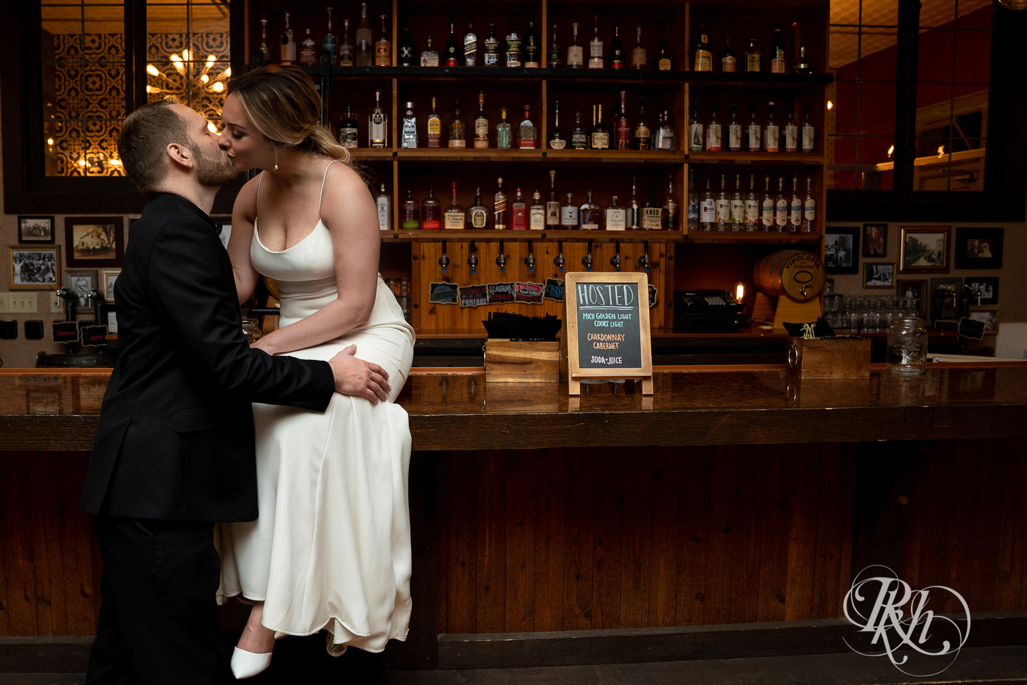 Bride and groom in black suit kiss on the bar at the 3 Ten Event Center in Faribault, Minnesota.