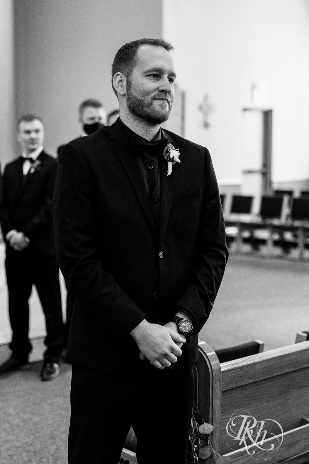 Groom sees bride walk down the aisle with dad in church wedding ceremony in Faribault, Minnesota.
