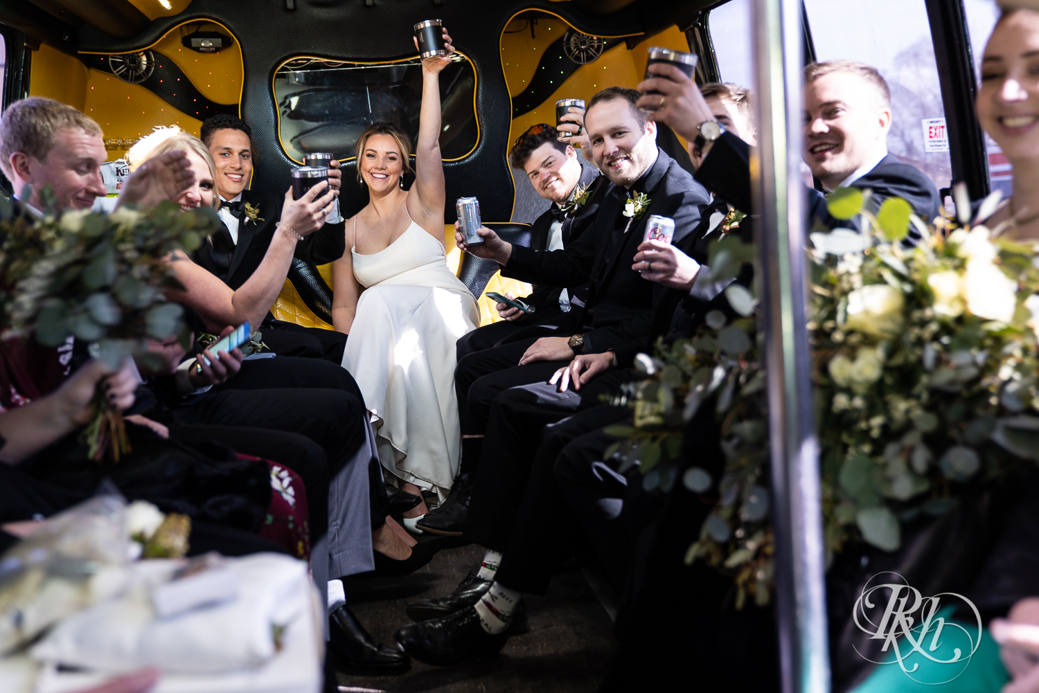 Bride and groom toast with wedding party on party bus after wedding ceremony in Faribault, Minnesota.