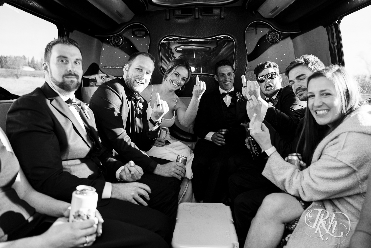 Bride and groom show rings with wedding party on party bus after wedding ceremony in Faribault, Minnesota.