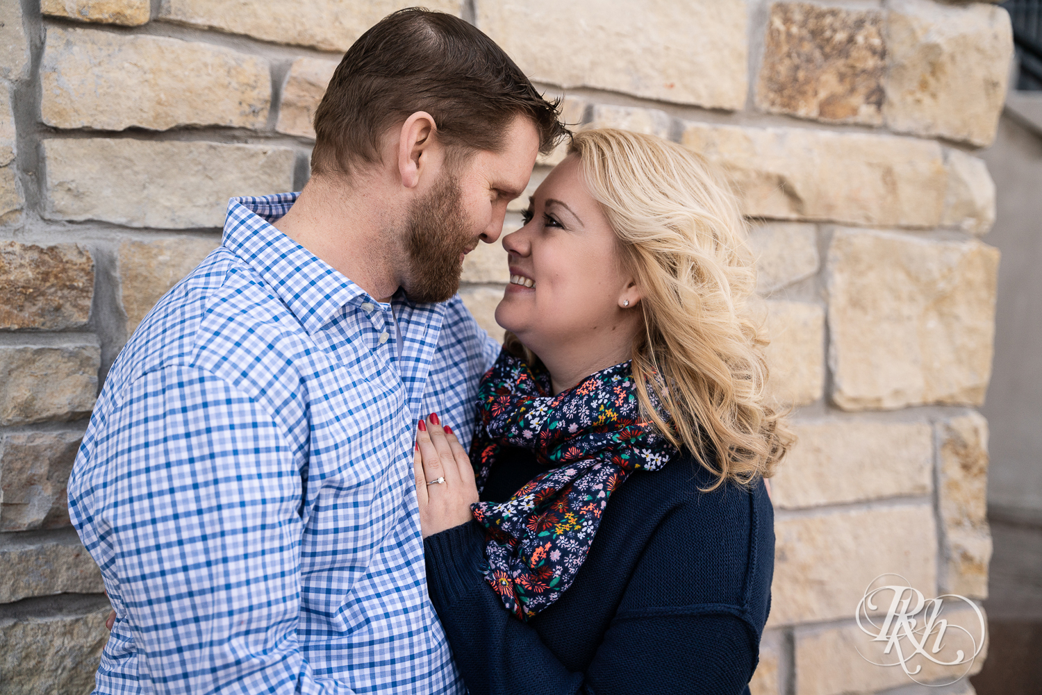 Blond woman and bearded man smile against brick wall in Stillwater, Minnesota.
