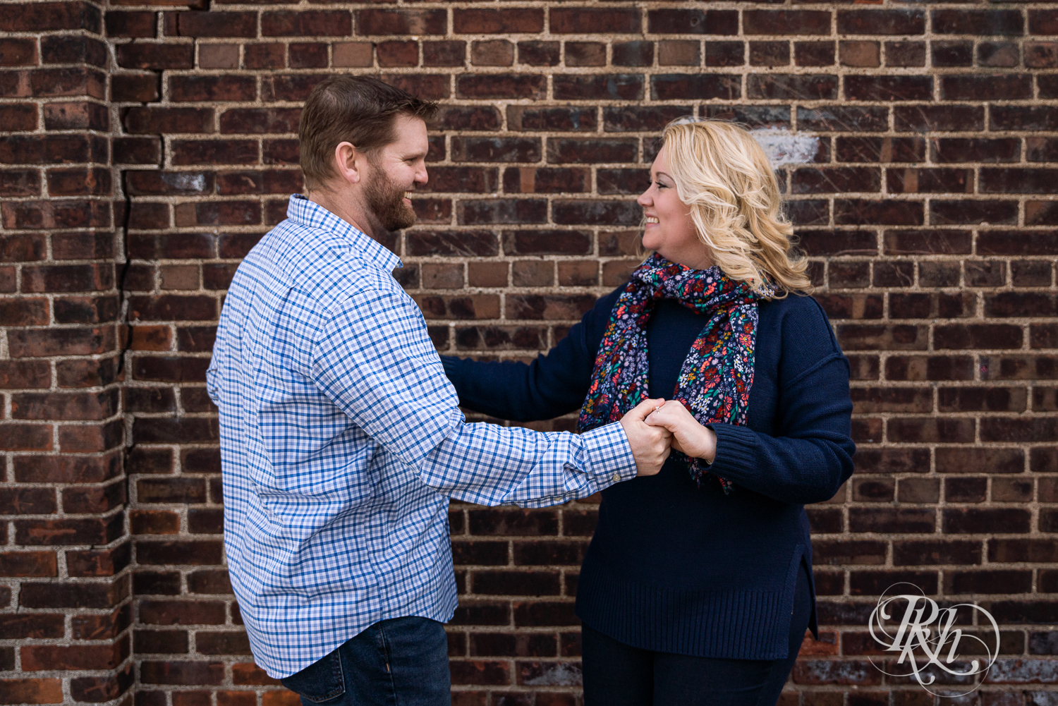 Blond woman and bearded man dance against brick wall in Stillwater, Minnesota.