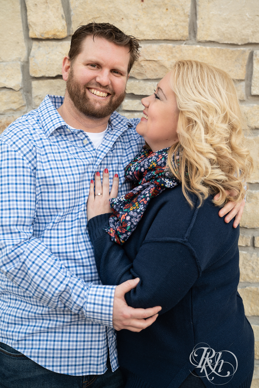 Blond woman and bearded man smile against brick wall in Stillwater, Minnesota.