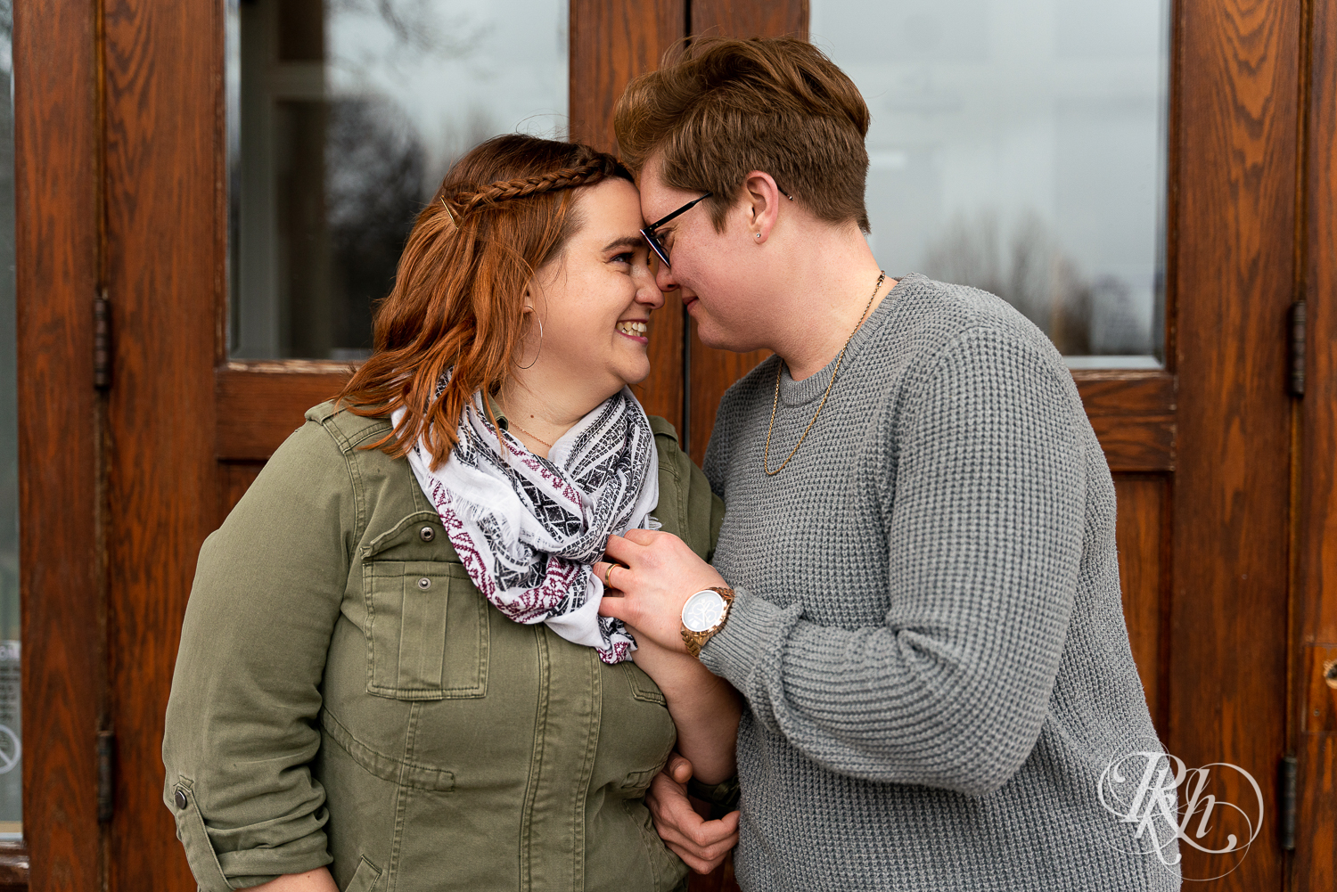Lesbian couple smile and hold hands in front of Saint Catherine's in Saint Paul, Minnesota. 