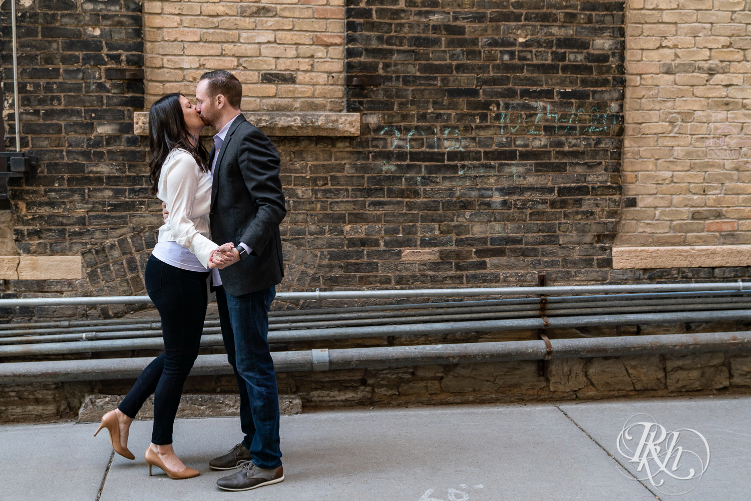 Man in suit and woman kiss in alley at Saint Anthony Main in Minneapolis, Minnesota.
