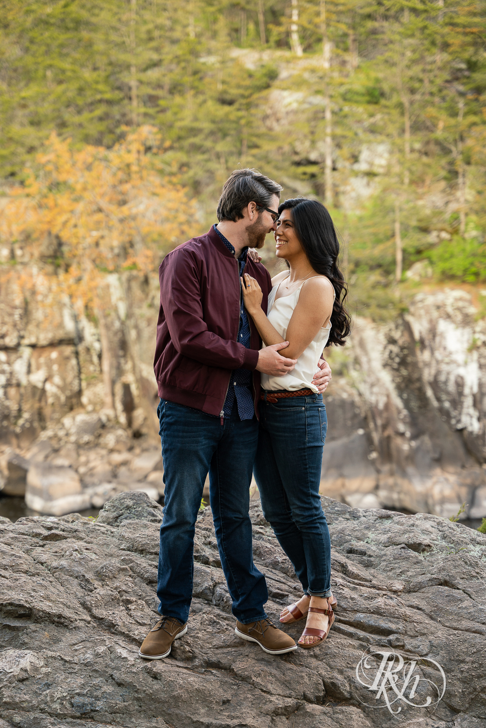 Man and woman in jeans laugh on cliff at Interstate State Park in Taylor's Fall, Minnesota.