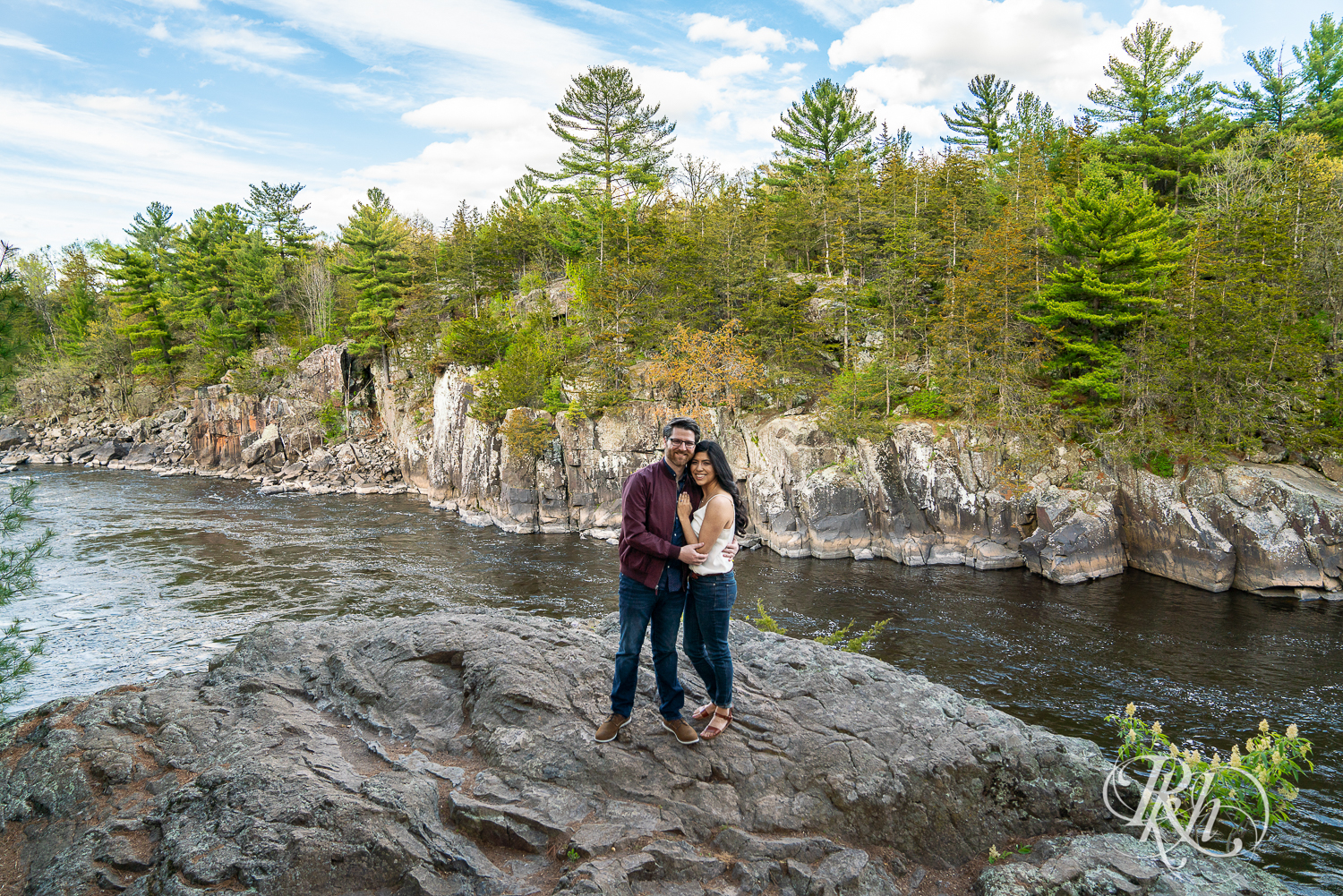 Man and woman in jeans laugh on cliff at Interstate State Park in Taylor's Fall, Minnesota.