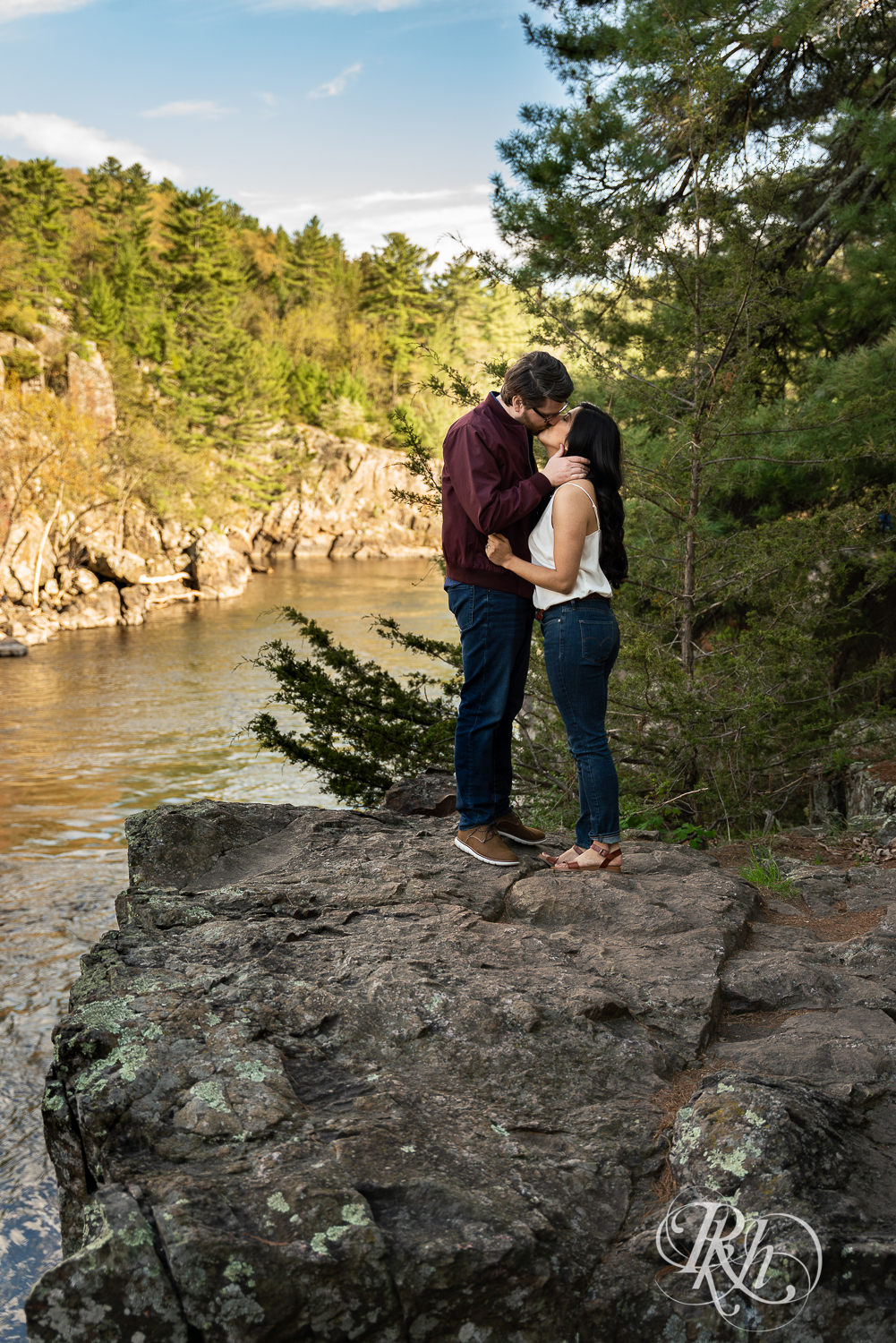 Man and woman in jeans kiss on cliff at Interstate State Park in Taylor's Fall, Minnesota.
