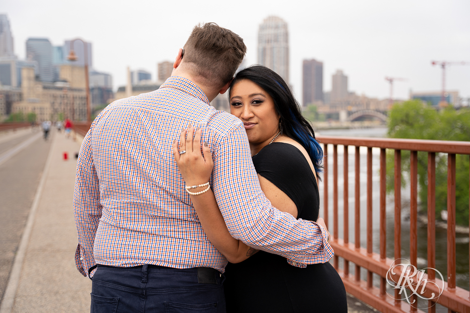 Man and Filipino woman smile on Stone Arch Bridge in Minneapolis, Minnesota.