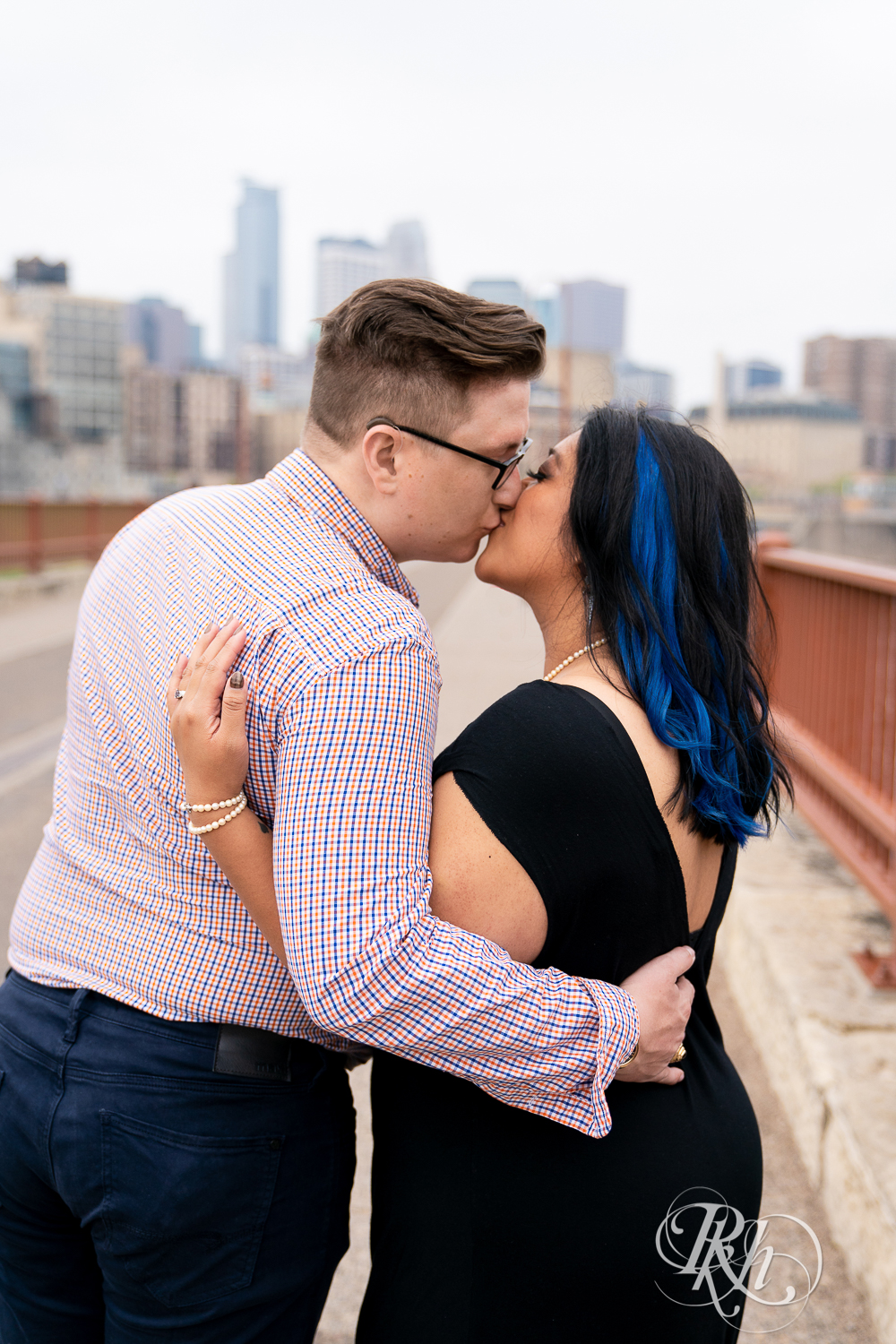 Man and Filipino woman kiss on Stone Arch Bridge in Minneapolis, Minnesota.