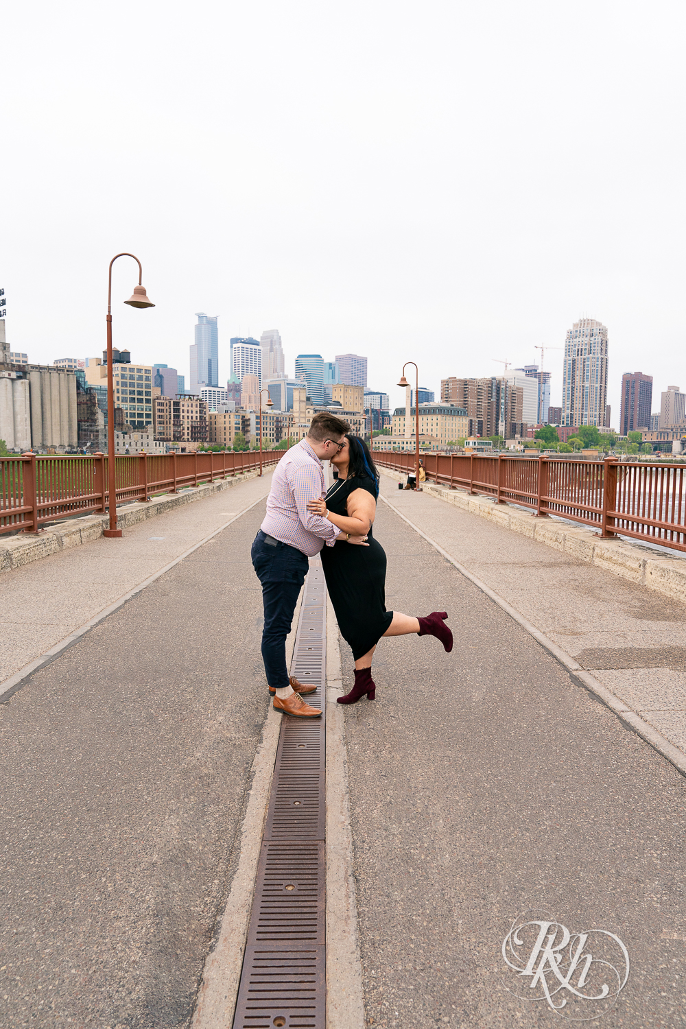 Man and Filipino woman kiss on Stone Arch Bridge in Minneapolis, Minnesota.