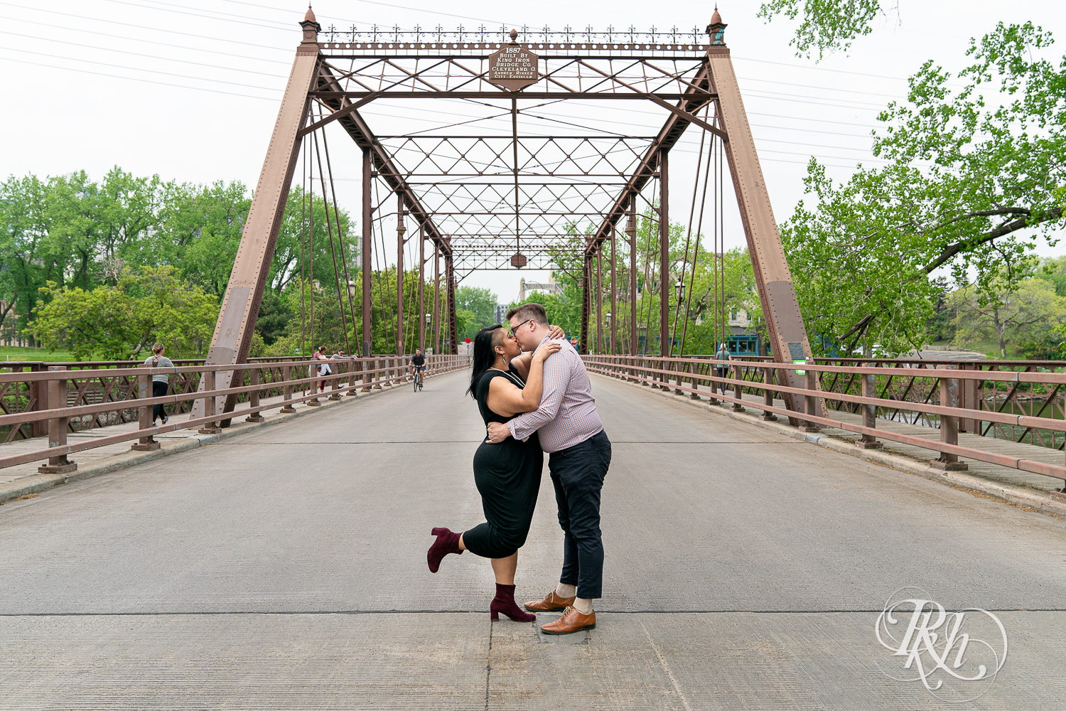 Man and Filipino woman kiss on bridge on Nicollet Island in Minneapolis, Minnesota.
