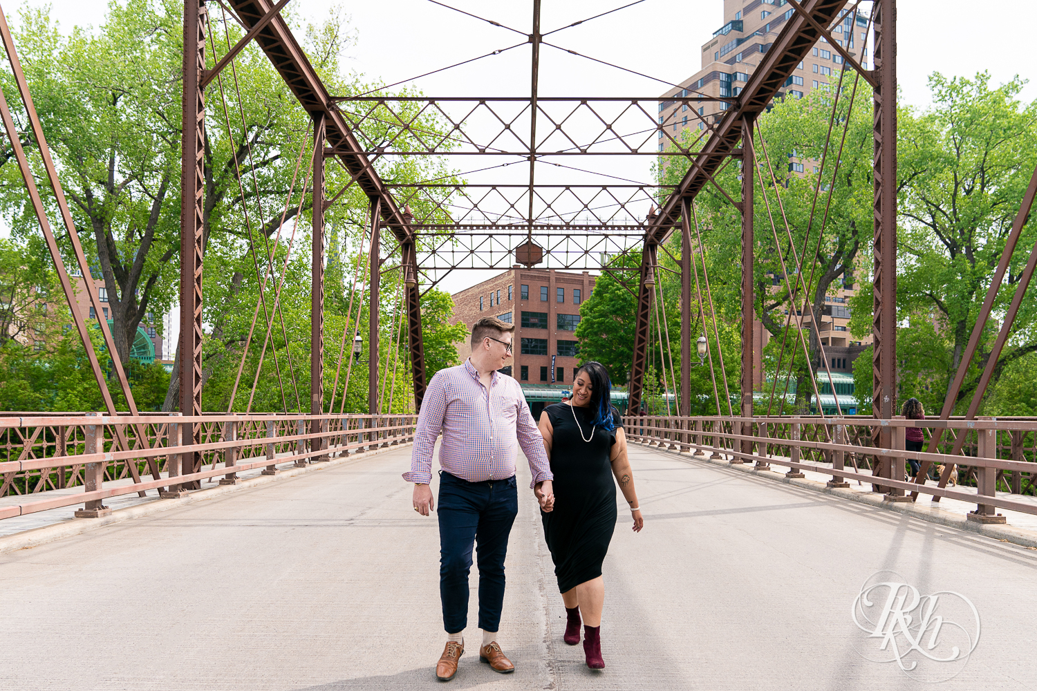 Man and Filipino woman walk across bridge on Nicollet Island in Minneapolis, Minnesota.