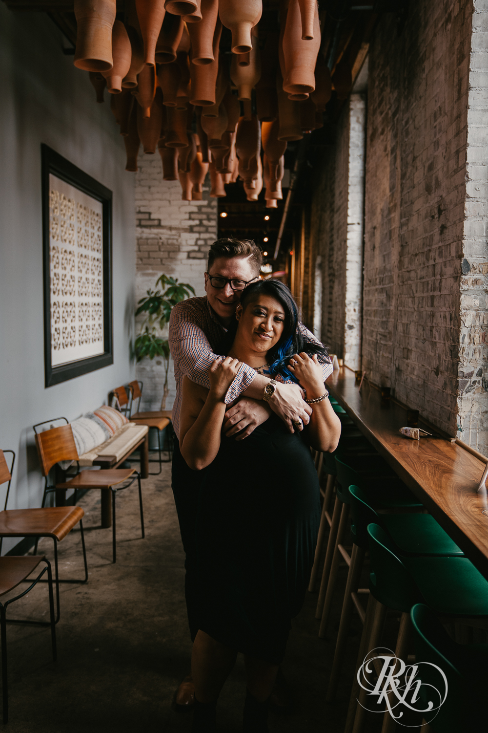 Man and Filipino woman hug during engagement session in restaurant in Minneapolis, Minnesota.