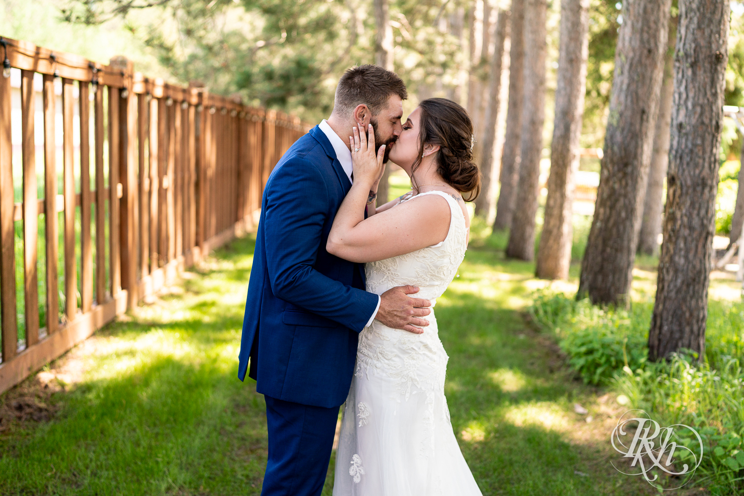 Bride and groom kiss with pine trees at their wedding at Pine Peaks Event Center in Pine River, Minnesota.