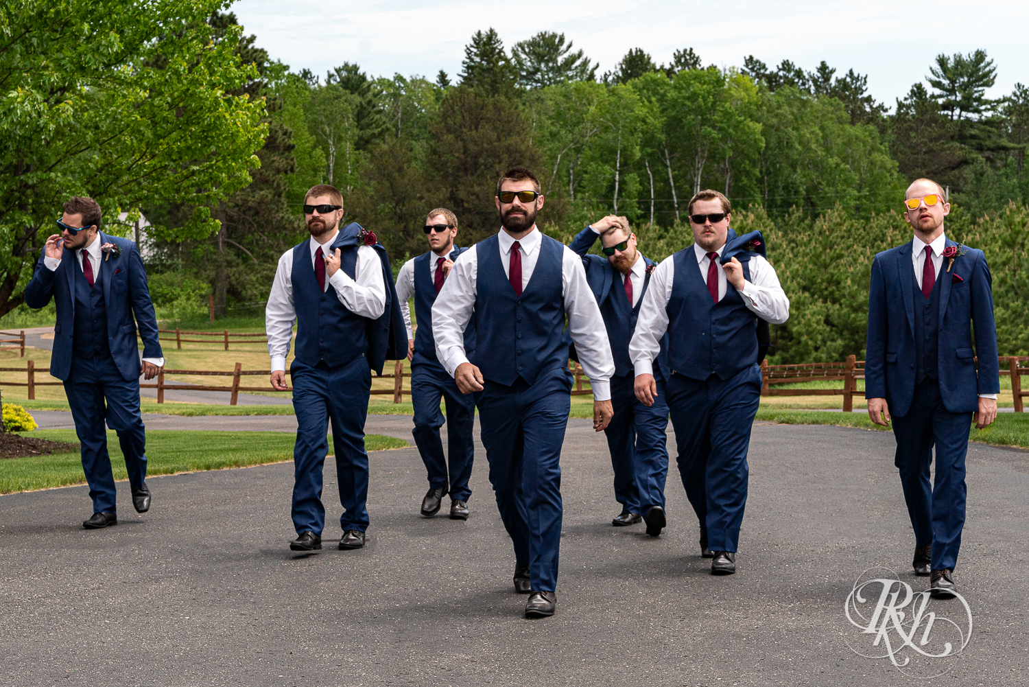 Wedding party in red dresses and blue suits walk down road at Pine Peaks Event Center in Pine River, Minnesota.