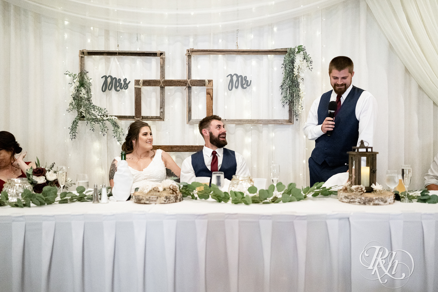 Bride and groom laugh during wedding speeches at Pine Peaks Event Center in Pine River, Minnesota.