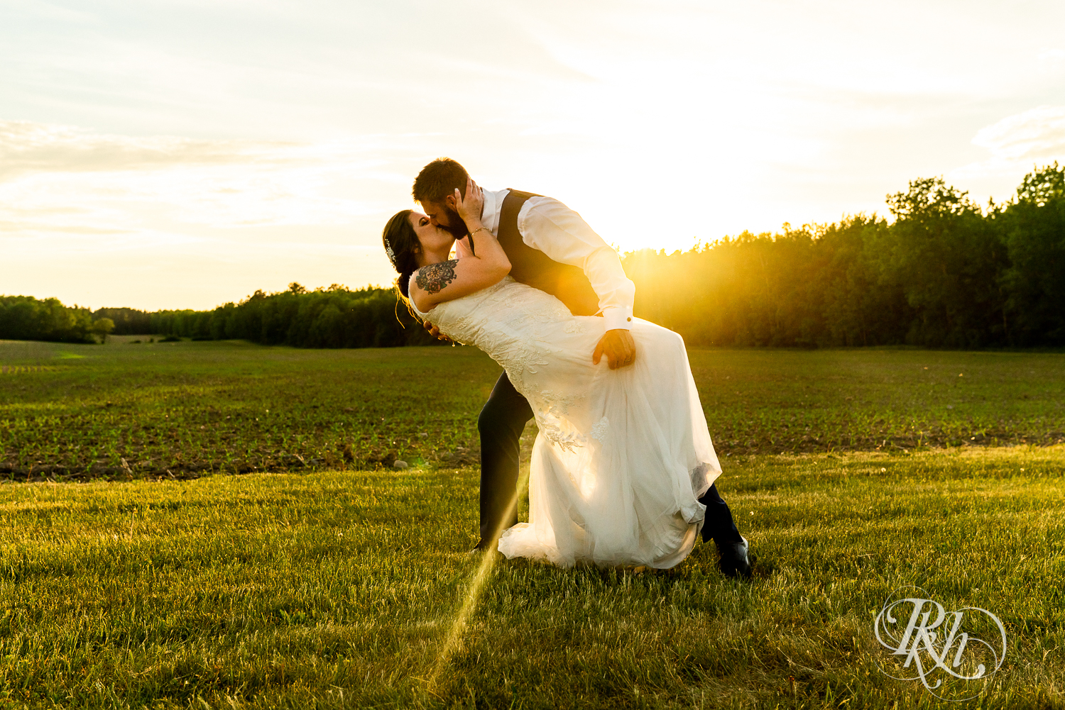Bride and groom dip and kiss during sunset at wedding at Pine Peaks Event Center in Pine River, Minnesota.