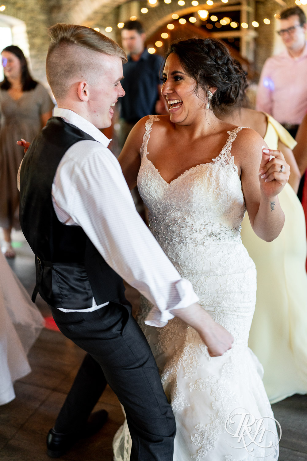 Guests dance with bride and groom at wedding reception at Mayowood Stone Barn in Rochester, Minnesota.