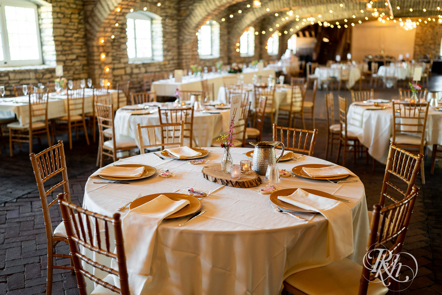 Indoor barn wedding reception setup with pink and white accents at Mayowood Stone Barn in Rochester, Minnesota.
