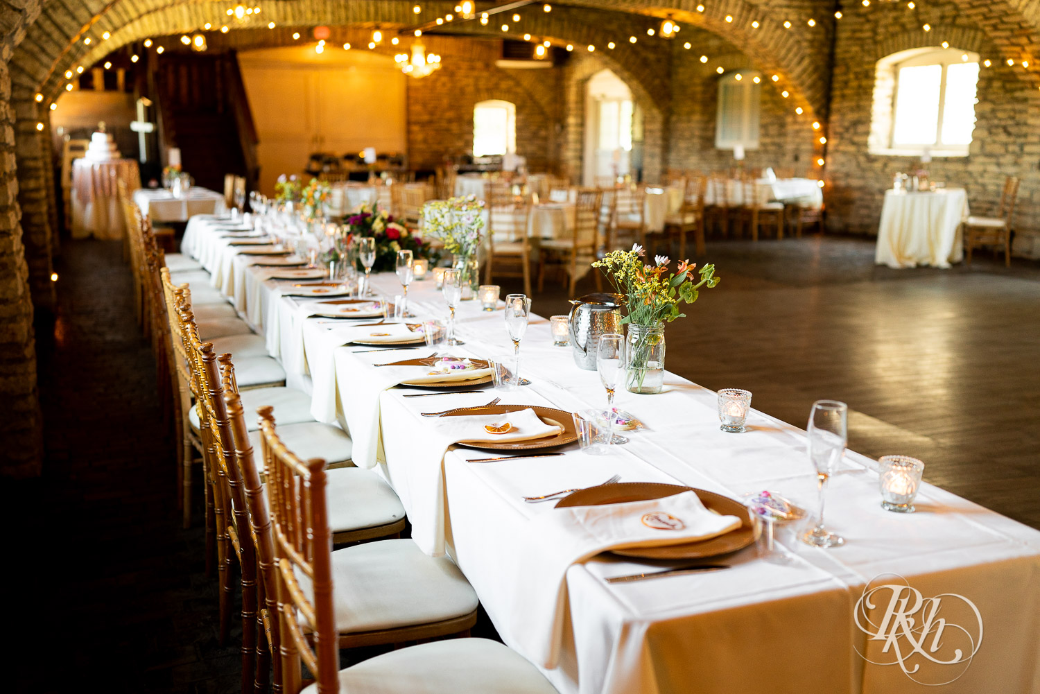 Indoor barn wedding reception setup with pink and white accents at Mayowood Stone Barn in Rochester, Minnesota.