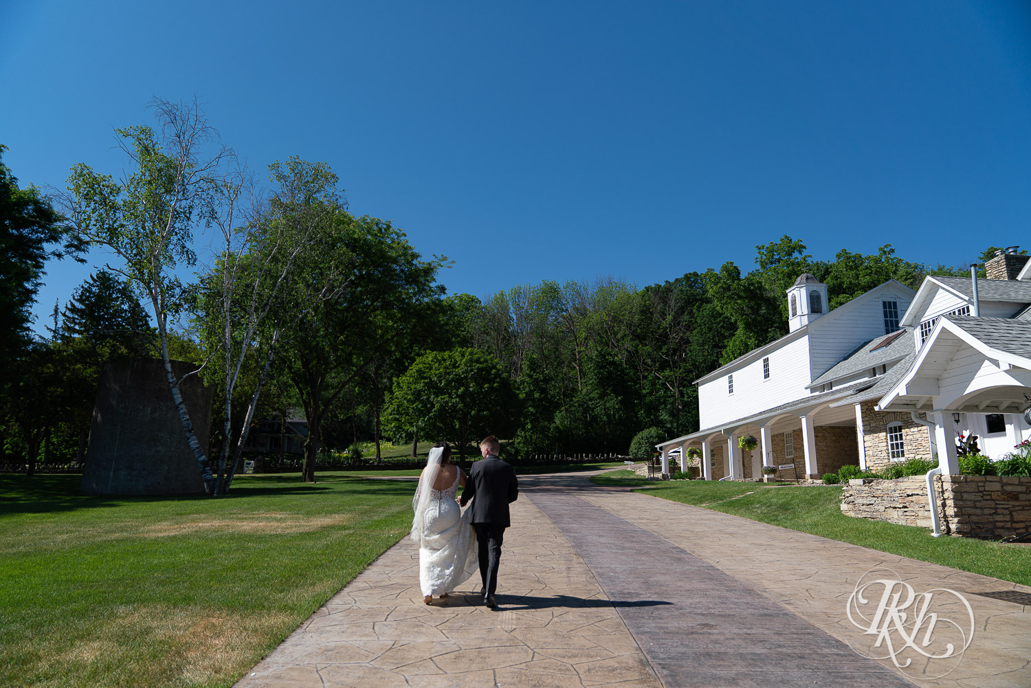 Bride and groom walking outside at summer brunch wedding at Mayowood Stone Barn in Rochester, Minnesota.