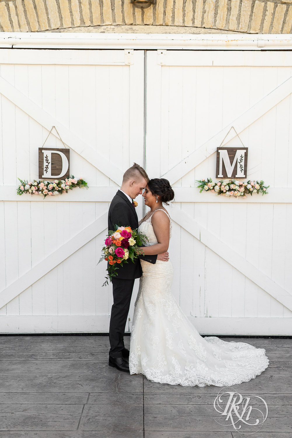 Bride and groom smiling in front of barn doors at wedding at Mayowood Stone Barn in Rochester, Minnesota.