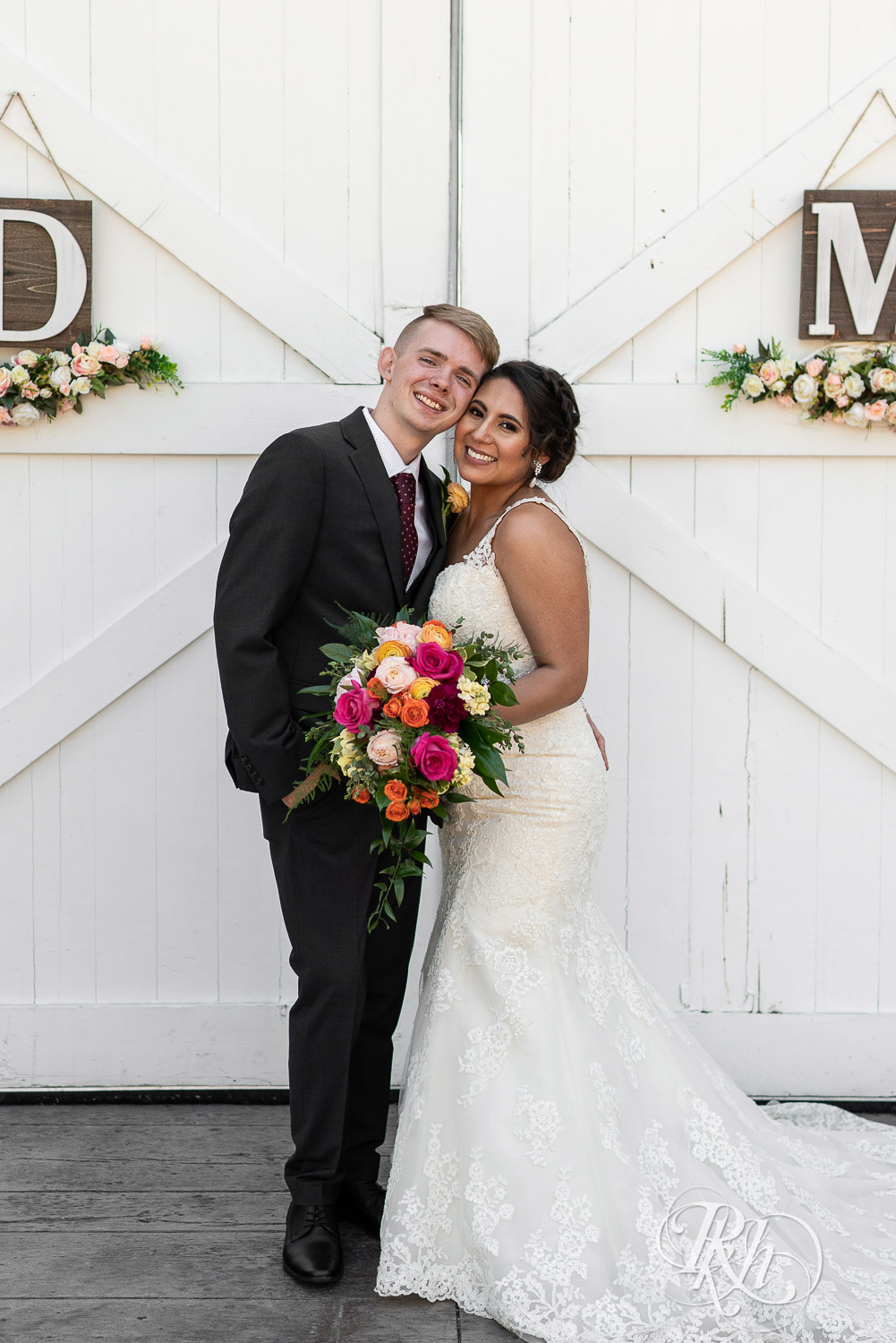 Bride and groom smiling in front of barn doors at wedding at Mayowood Stone Barn in Rochester, Minnesota.