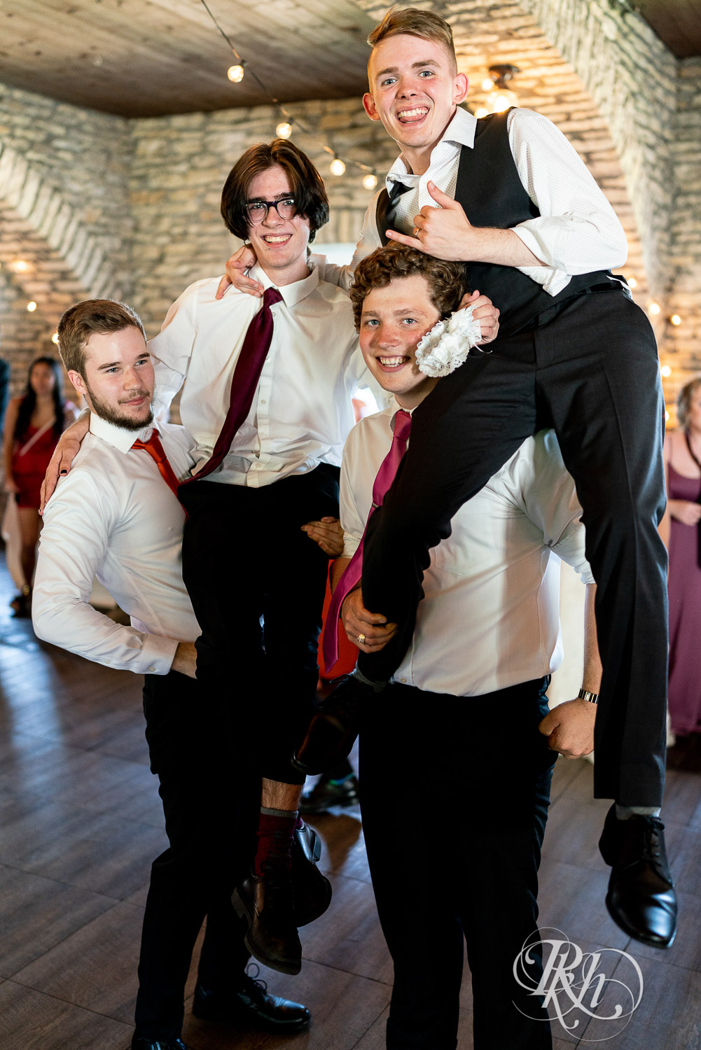 Groomsmen holding groom on shoulders at wedding reception at Mayowood Stone Barn in Rochester, Minnesota.