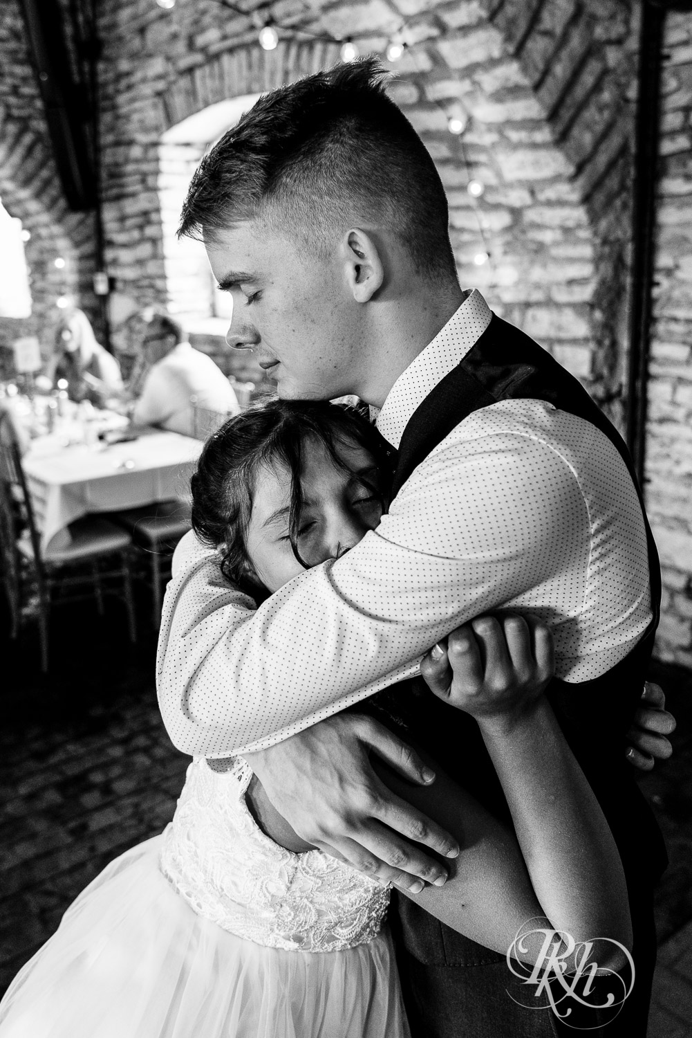 Groom hugging flower girl at wedding reception at Mayowood Stone Barn in Rochester, Minnesota.